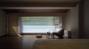 A bedroom with a large window, a bed, a reading chair, and a small table. - Liuyang Yunxi Fenglin Valley Homestay (Changsha)