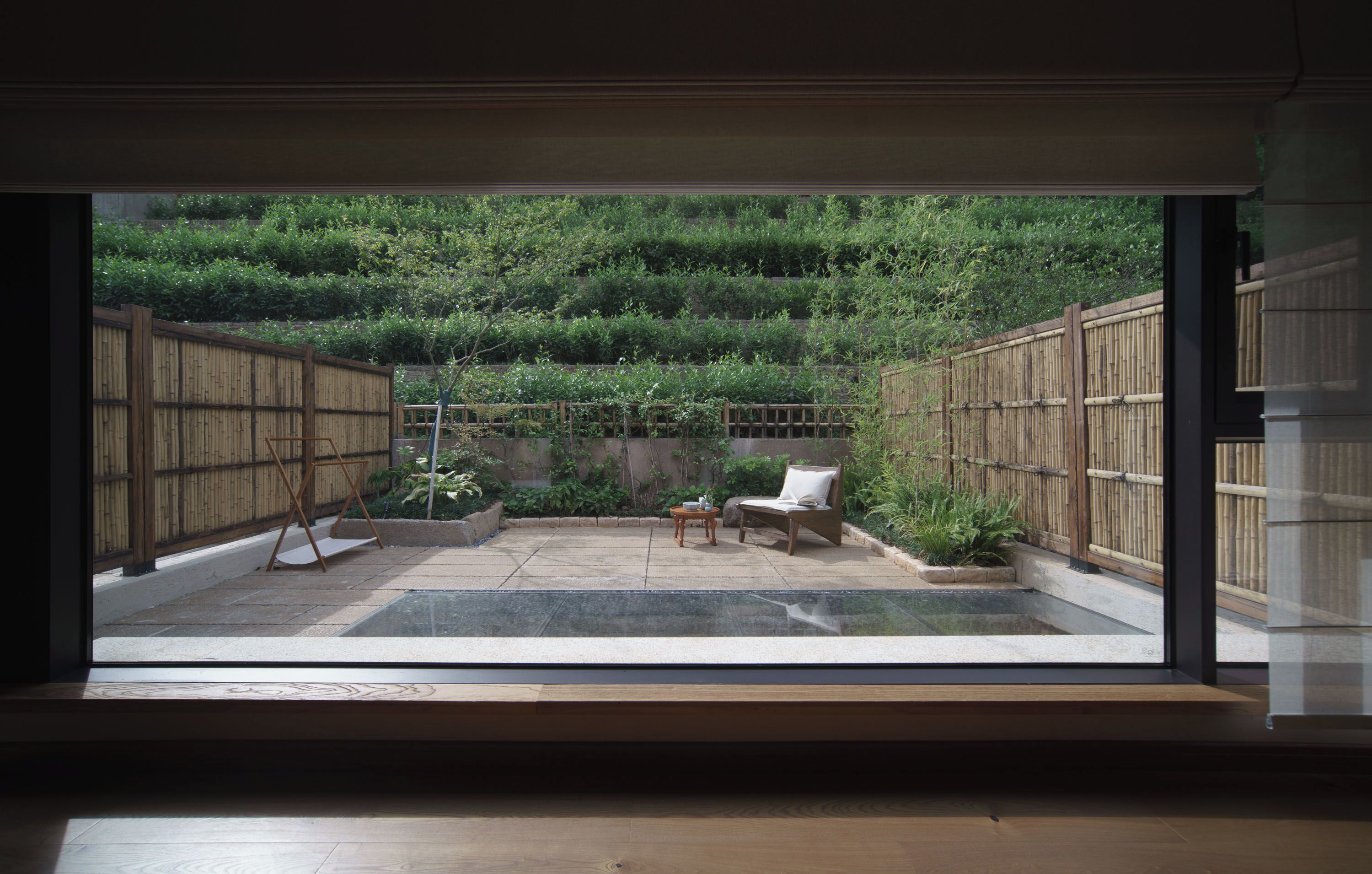A room with a large window overlooking a bamboo garden.