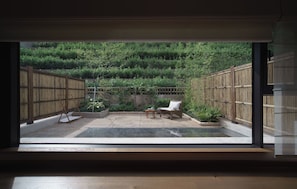 A room with a large window overlooking a bamboo garden.