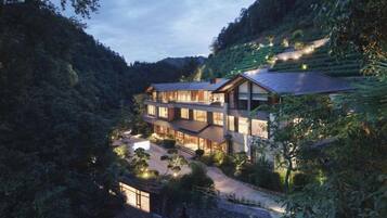 A multi-story building with a modern design, surrounded by lush greenery and terraced fields.