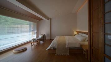 A bedroom with a bed, bedside table, and a window with blinds.