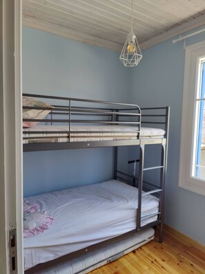 Een stapelbed met een metalen frame, een hanglamp en een raam met uitzicht.