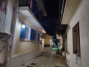 A narrow alleyway with buildings on either side, a motorcycle parked on the right, and a street lamp on the left. - 4-bedroom house with a garden in the center of Lefkada (Λευκάδα)