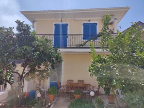 Een gebouw met twee verdiepingen, een balkon, een terras buiten en potplanten.