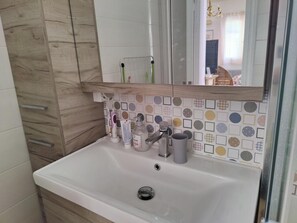 A bathroom with a white sink, wooden cabinet, and a mirror above it. - 4-bedroom house with a garden in the center of Lefkada (Λευκάδα)