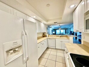 A kitchen with white cabinets, a refrigerator, a dishwasher, and a countertop with a sink. - Links N at Harbor Village B507 (Ponce Inlet)