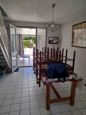 Un comedor con mesa y sillas, una escalera y vistas al exterior.