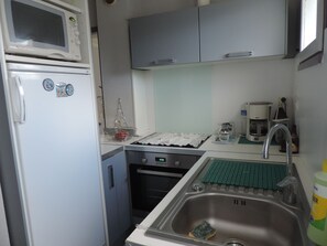 Una cocina compacta equipada con microondas, horno, pileta y cafetera.