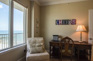 A room with a view of the beach, a desk with a lamp, a chair, and a cushion with 'HOME' on it. - Salida del Sol 1002 in Daytona Beach Shores, FL (Daytona Beach Shores)