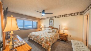 A bedroom with a bed, two bedside tables with lamps, a window with a view, and a ceiling fan. - #1004 Seychelles 3/3 Oceanfront Traffic Free Beach (Daytona Beach Shores)