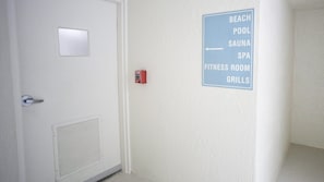 A door with a fire alarm and a sign indicating amenities such as a beach pool, sauna, spa, fitness room, and grills. - #1004 Seychelles 3/3 Oceanfront Traffic Free Beach (Daytona Beach Shores)
