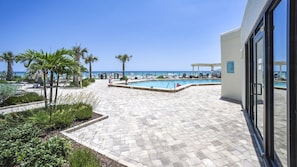 A pool area with a clear view of the ocean, surrounded by palm trees and lounge chairs. - #1004 Seychelles 3/3 Oceanfront Traffic Free Beach (Daytona Beach Shores)