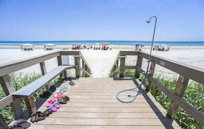 A wooden deck leading to a beach with a hose on the right side. - #1005 Seychelles 2/2 Oceanfront Traffic Free Beach (Daytona Beach Shores)