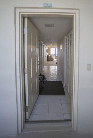 A narrow hallway with a door labeled '1005' leading to a room. A bicycle is parked against the wall, and a black mat is on the floor. - #1005 Seychelles 2/2 Oceanfront Traffic Free Beach (Daytona Beach Shores)