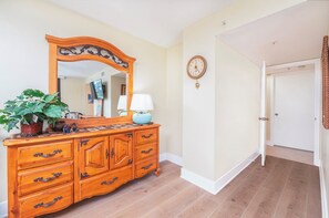 Una habitación con un aparador de madera, un espejo, un reloj y una planta en maceta.