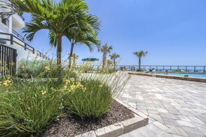 A paved outdoor area with a pool, palm trees, and a clear view of the sea. - #101 Seychelles 2/2 Oceanfront Traffic Free Beach (Daytona Beach Shores)