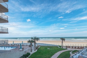 A beachfront property with a swimming pool, lounge chairs, and a view of the ocean. - #101 Seychelles 2/2 Oceanfront Traffic Free Beach (Daytona Beach Shores)