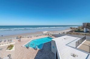 Una piscina al terrat amb vistes a la platja i l'oceà.