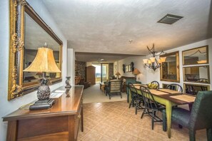 A dining area with a wooden table and chairs, a lamp, and a mirror on the wall. - #301 Seychelles Oceanview Traffic Free Beach (Daytona Beach Shores)