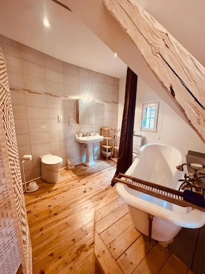 A modern bathroom with a wooden floor, a white bathtub, a sink, and a toilet. - La Maison du Chat Perché  (INGERSHEIM)