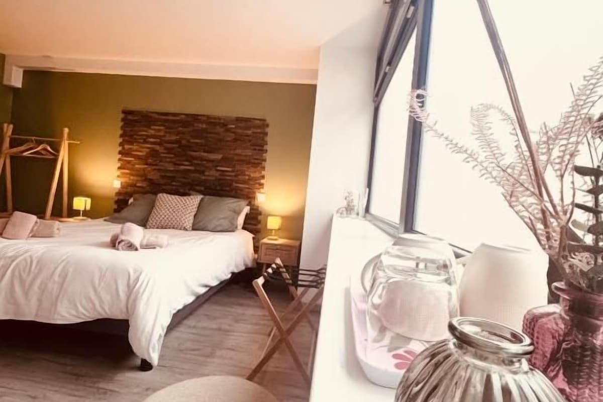 A bedroom with a bed, bedside table, and a window with curtains.
