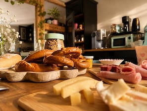 A wooden cutting board with pretzels, cheese, and sliced meats. - La Maison du Chat Perché  (INGERSHEIM)