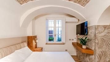 Een slaapkamer met een groot bed, een houten hoofdbord, een raam, een flatscreen televisie en een plant op een plank.