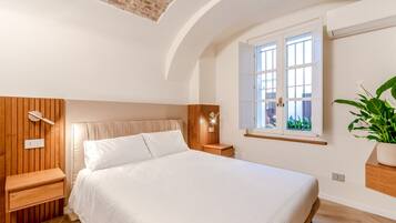 Een slaapkamer met een bed, nachtkastjes, een raam met uitzicht en een plant.