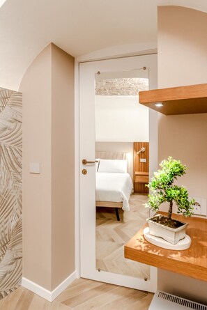 Een slaapkamer met een bed, nachtkastje, een bloempot en een houten plank.