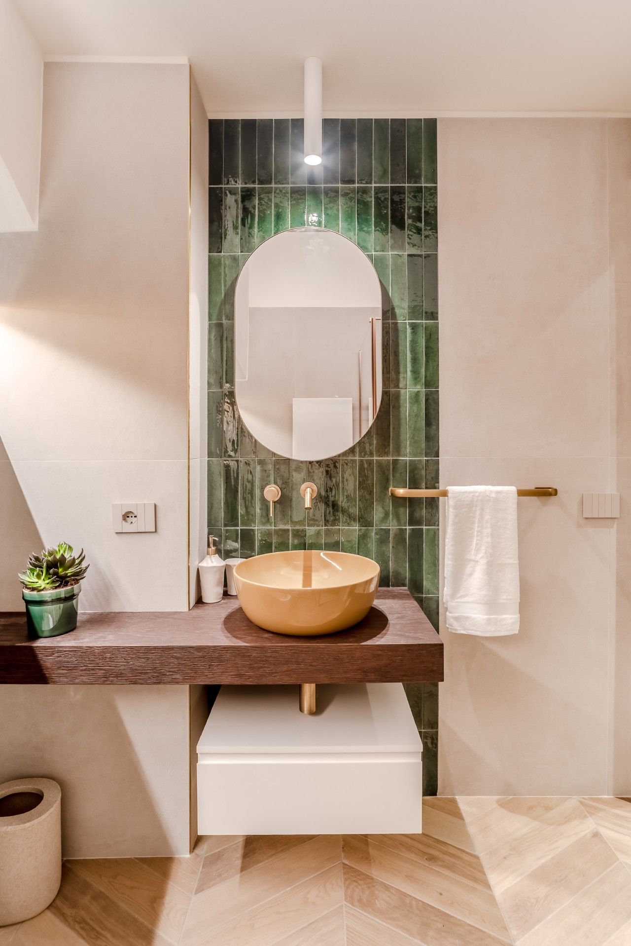 A modern bathroom with a round sink, a mirror, and a towel rack.