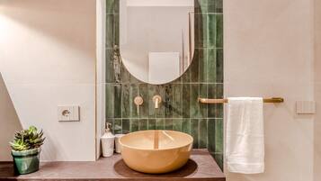 A modern bathroom with a round sink, a mirror, and a towel rack.