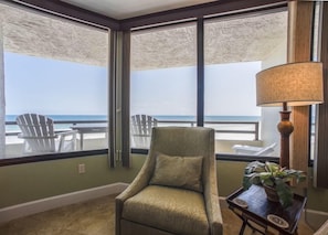 A room with a view of the beach, a green armchair, a lamp, and a small table with a plant. - #304 Seychelles 3/3 Oceanfront Traffic Free Beach (Daytona Beach Shores)
