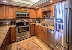A kitchen with wooden cabinets, stainless steel appliances, granite countertops, and a built-in microwave. - #304 Seychelles 3/3 Oceanfront Traffic Free Beach (Daytona Beach Shores)