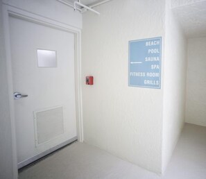 A hallway with a door and a sign indicating amenities such as a beach pool, sauna, spa, fitness room, and grills. - #304 Seychelles 3/3 Oceanfront Traffic Free Beach (Daytona Beach Shores)