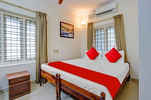 A hotel room with a wooden bed, red pillows, a nightstand, and a painting on the wall. - Hotel O Le Fort (Thiruvananthapuram)