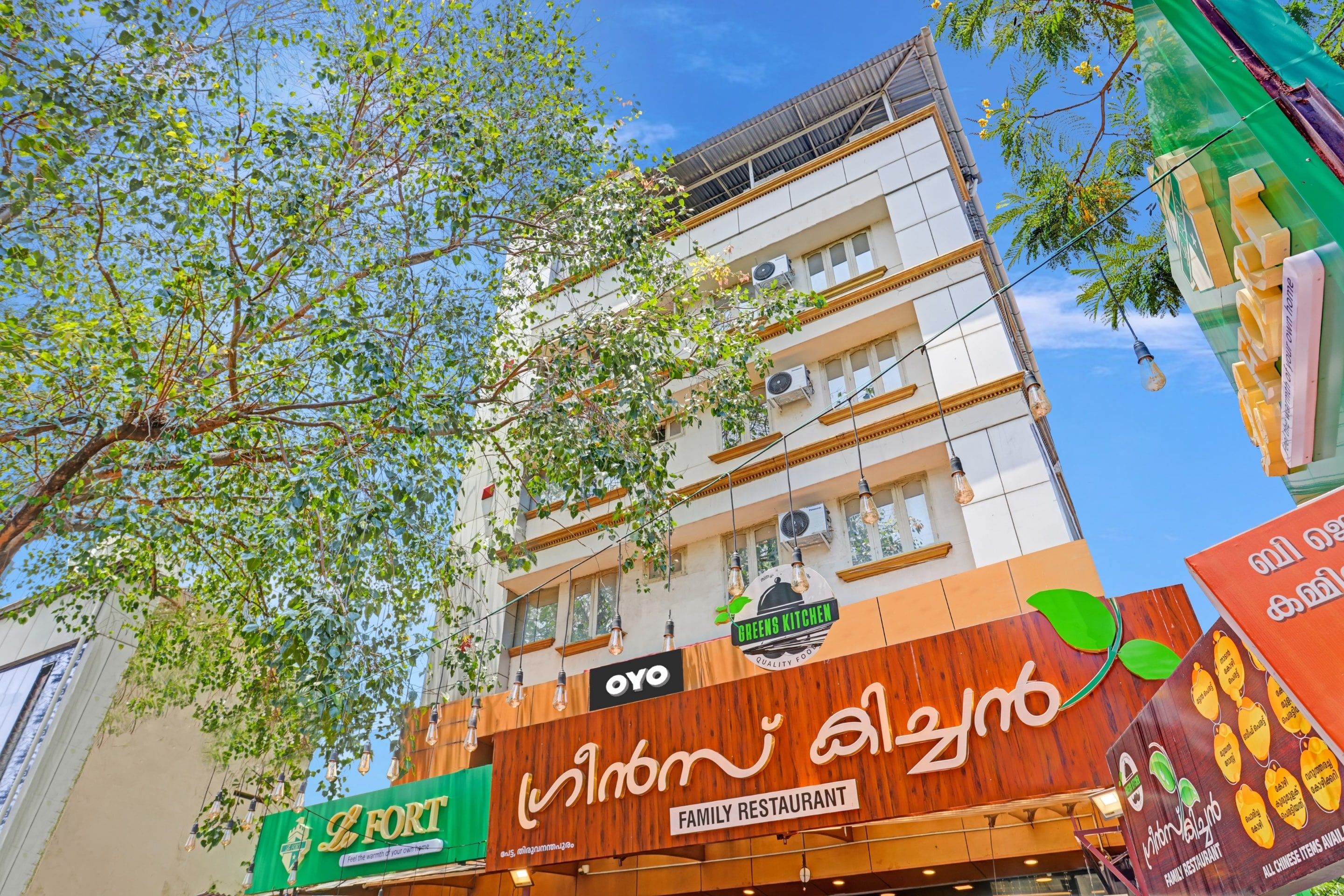 Un immeuble à plusieurs étages qui abrite un restaurant appelé « Oyo Greens Kitchen » au rez-de-chaussée.