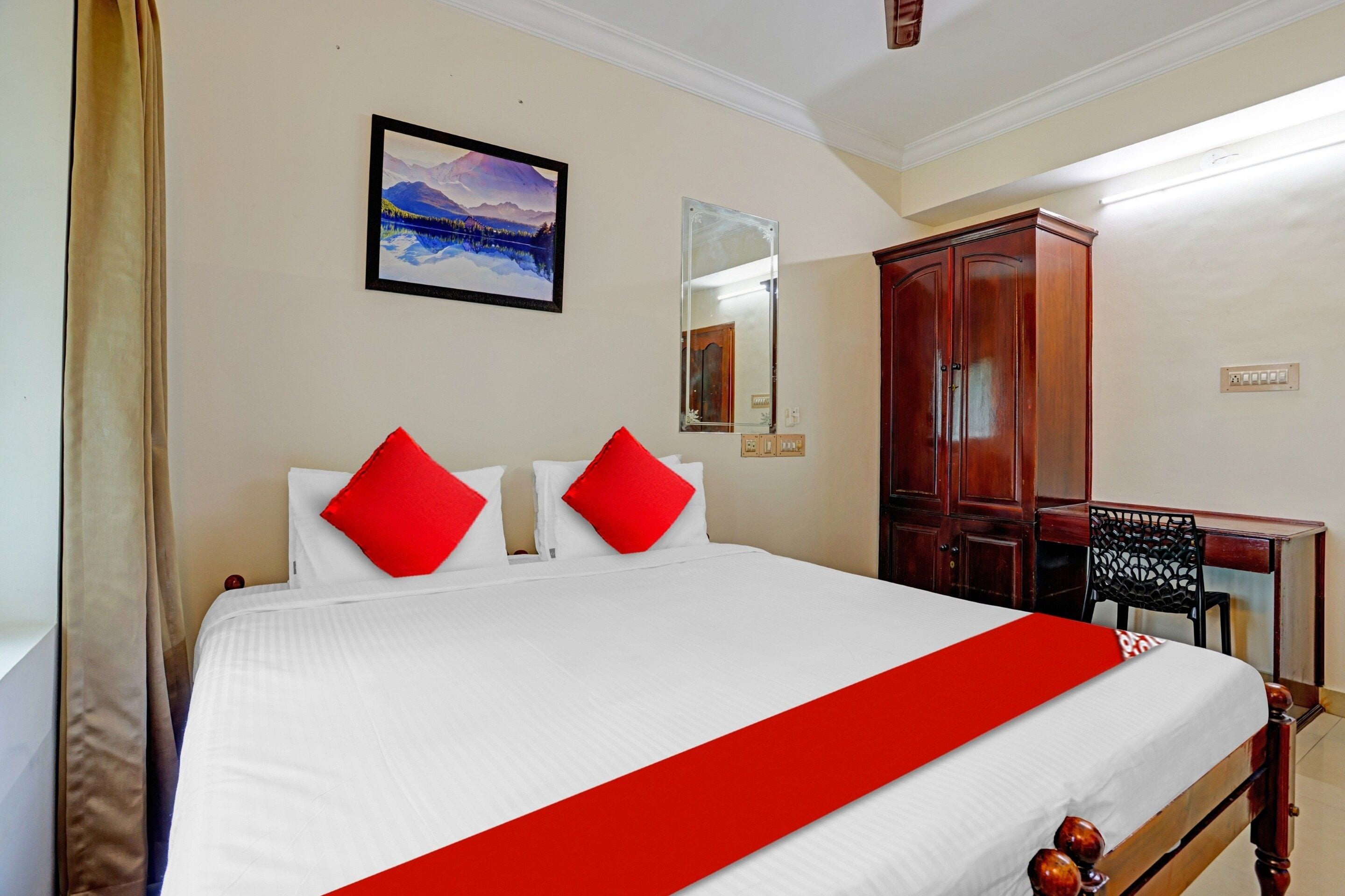 A hotel room with a bed, a desk, a wardrobe, and a painting on the wall.