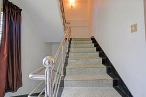 A staircase with a metal handrail and a light fixture above. - Hotel O Le Fort (Thiruvananthapuram)