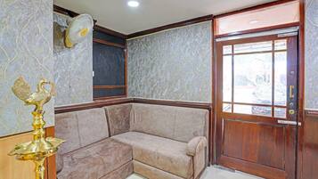 A corner room with a beige sofa, a wooden door, and a marble-patterned wall.
