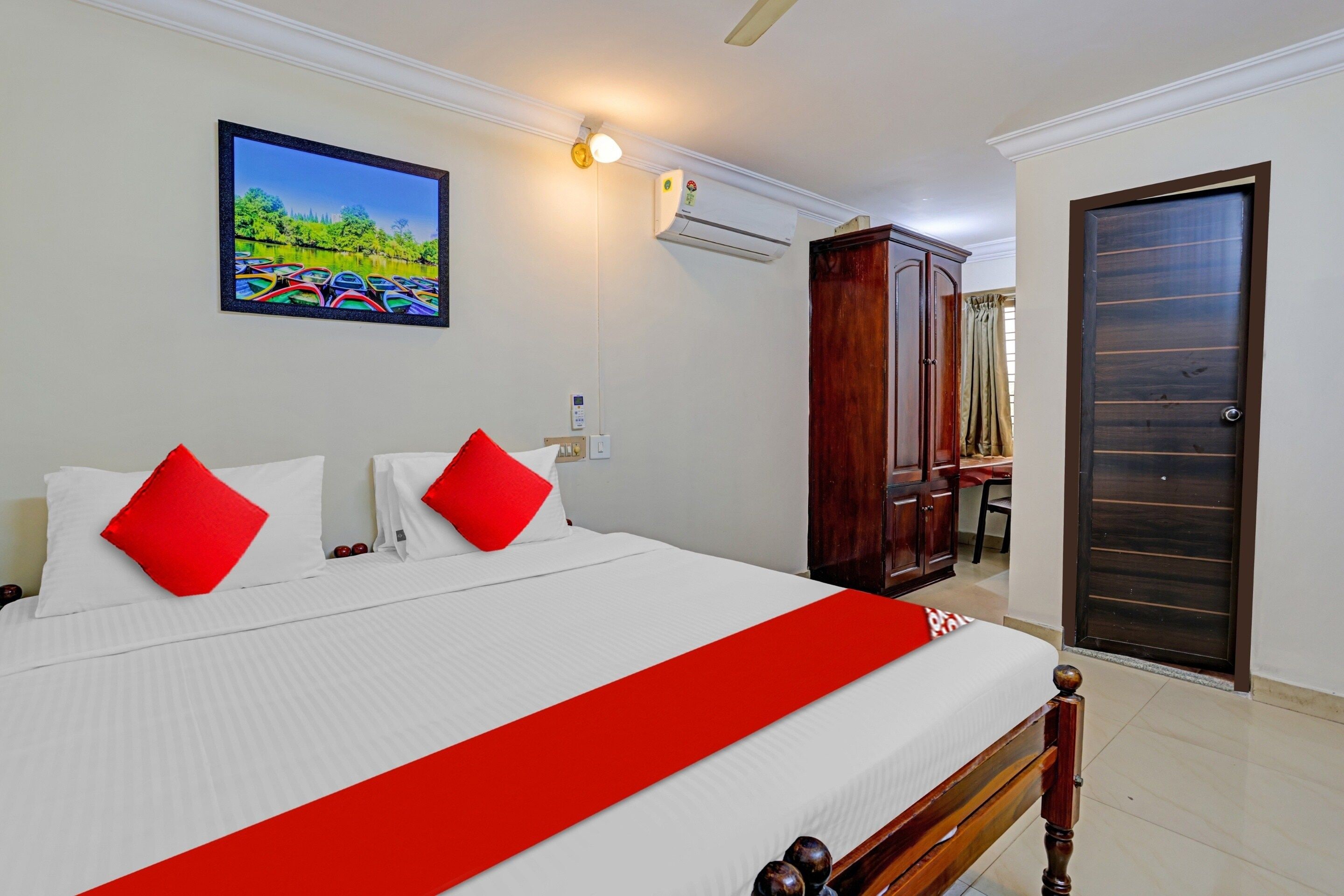 Una habitación de hotel con una cama, un cuadro, un equipo de aire acondicionado y un armario de madera.