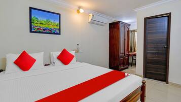 Una habitación de hotel con una cama, un cuadro, un equipo de aire acondicionado y un armario de madera.