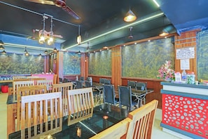 A restaurant with wooden furniture, hanging lights, and a counter with a menu. - Hotel O Le Fort (Thiruvananthapuram)