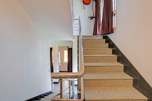 A staircase with a handrail and a wall-mounted fire hose reel. - Hotel O Le Fort (Thiruvananthapuram)
