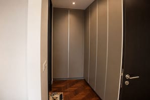 Ein schmaler Flur mit Holzboden, einer dunklen Tür rechts und einem Lichtschalter links.