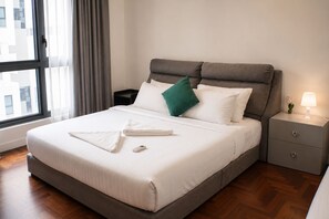A neatly made bed with white bedding, a remote control, and a green pillow. - Skyline Service Suite KLCC at The Mews (Kuala Lumpur)
