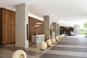 A modern hotel lobby with a reception desk, a row of spherical vases, and a car parked outside. - Skyline Service Suite KLCC at The Mews (Kuala Lumpur)