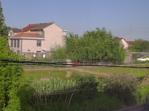 Un edifici tradicional amb teules, envoltat de vegetació i una massa d'aigua.