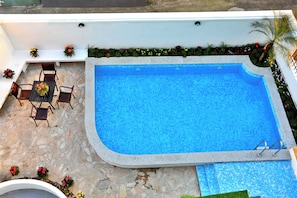 Piscina amb terrassa de pedra, envoltada de plantes i flors en testos.