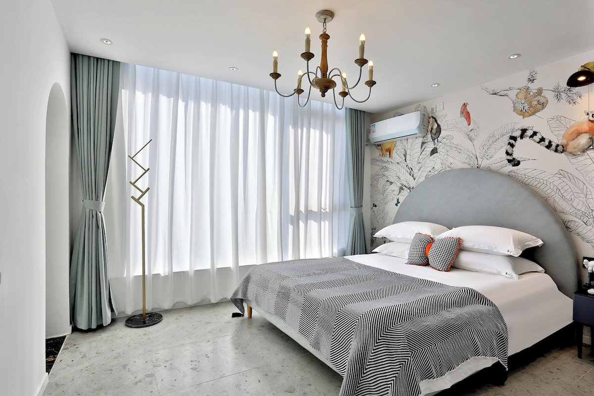 A modern bedroom with a large bed, a chandelier, and a mural on the wall.