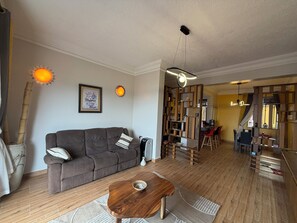 A living room with a sofa, a coffee table, a dining area with chairs, and a kitchen visible through an open door. - Lake view 2-bedroom apartment with power backup in vibrant Kampala neighborhood (Kampala)